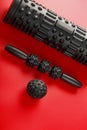 Set of Black lumpy foam massage roller, body roller, rubber ball on red background Royalty Free Stock Photo