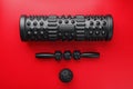 Set of Black lumpy foam massage roller, body roller, rubber ball on red background Royalty Free Stock Photo