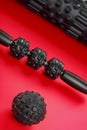 Set of Black lumpy foam massage roller, body roller, rubber ball on red background Royalty Free Stock Photo