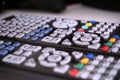 Set of black remote controls with colorful buttons on white surface as a symbol of home entertainment when watching televisi