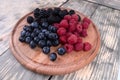 A set of blackberries, blueberries and raspberries laying on a wooden plate Royalty Free Stock Photo