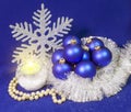 Set blue beautiful glass New Year`s balls, brilliant tinsel, the burning candle and a pearl beads on a blue background - New Year Royalty Free Stock Photo