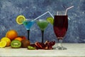 Set of blue red green cocktails in martini glasses with ice and fresh fruit kiwi pomegranate lin on a gray background. Set of cock Royalty Free Stock Photo