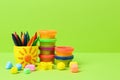 Set of bright play dough with mold and colorful pencils on light green background. Space for text