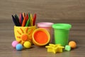 Set of bright play dough with mold and colorful pencils on wooden table