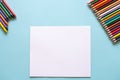 A set of bright stationery items on a blue background. Colored pencils and white paper Royalty Free Stock Photo