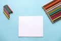 A set of bright stationery on a blue background. colored pencils and white paper Royalty Free Stock Photo