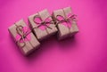 Set of brown gift boxes. Wrapped in craft paper and tied by hemp cord. Bright pink background and carton hearts decorative card. Royalty Free Stock Photo