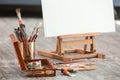 Set of brushes and paints with easel on floor in artist's workshop Royalty Free Stock Photo