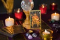 Burning colorful candles with devil tarot cards and stones on table