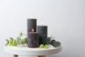 Set of burning candles, flowers and green branches on table at white wall Royalty Free Stock Photo