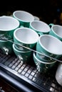 set of ceramic colored cups or mugs heating on professional coffee machine Royalty Free Stock Photo