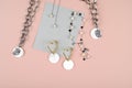 Set of chain chokers with pearls, earrings on pink surface. Trendy stylish jewelry. Female blog