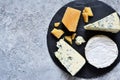 A set of cheeses: brie, blue cheese, parmesan, camembert on a slate board. Plate with delicacies. View from above Royalty Free Stock Photo