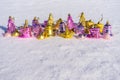 Set of Christmas toys in gold and pink colors lying on white fresh snow in winter sunny day. New year decorations, greeting card Royalty Free Stock Photo