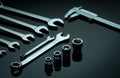 Set of chrome wrenches or spanners, hexagon socket, and vernier caliper on dark table in workshop. Chrome vanadium spanner wrench