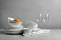 Set of clean dishware, glasses and lemon on grey table Royalty Free Stock Photo