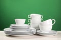 Set of clean dishware on white table against green background Royalty Free Stock Photo