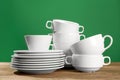 Set of clean dishware on wooden table against green background