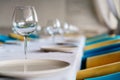 Set of clean empty wine glasses and plates on dining table with colorful chairs on a restaurant interior pastel background. Close Royalty Free Stock Photo