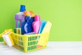 Set of cleaning products and detergents for cleaning in a yellow basket on a green background, a place for your inscription