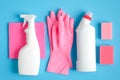 Set of cleaning supplies on blue background. Flat lay pink rag and sponge, rubber gloves, cleaner spray bottle, detergent. House Royalty Free Stock Photo