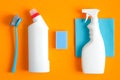 Set of cleaning supplies on orange background. Flat lay blue rag, sponge, brush, pink rubber gloves, cleaner spray bottle, Royalty Free Stock Photo