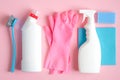 Set of cleaning supplies on pink background. Flat lay blue rag, sponge, brush, pink rubber gloves, cleaner spray bottle, detergent