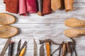 Set of cobbler tools and a lot of brightly colored leather in rolls on wooden background. Space for text.