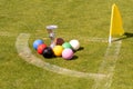 A set of colored croquet balls and a winners cup on the green lawn, blurred background