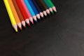 A set of colored pencils on a black wooden background. Sharpened bright pencils Royalty Free Stock Photo
