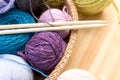 Set of colored yarn balls and needles on straw plate close up