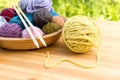 Set of colored yarn balls and needles on straw plate close up Royalty Free Stock Photo