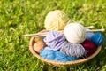 Set of colored yarn balls and needles on straw plate