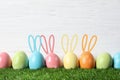 Set of colorful eggs with Easter bunny ears on green grass against wooden background Royalty Free Stock Photo