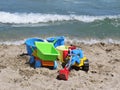 Set of Colorful Kid Child Toys Laying on Sandy Beach with Waves in Background
