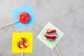 Set of colorful lollipops placed atop a stack of sticky notes