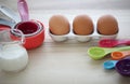 Set of colorful measuring cups, measuring spoons, three eggs and milk in glasses jar.