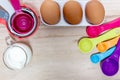 Set of colorful measuring cups, measuring spoons, three eggs and milk.