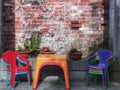 Set of colourful plastic furniture in front of a rough built brick wall