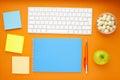 Set of colourful stickers, white keyboard, notebook and snacks.