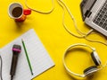 Set consisting of red coffee cup, music notebook, microphone, headphones, notebook and pencil on a yellow surface Royalty Free Stock Photo