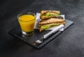 set consisting of two sandwiches malted bread with vintage cheddar cheese, pickles, red onion, tomato, lettuce, orange juice