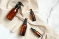 Set of cosmetic amber glass bottles with beige fabric on marble table. Flat lay, top view. Beauty products for man skin care,