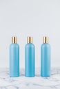 Set of cosmetic bottles, collection of three empty blue bottles of shampoo or lotion on white background