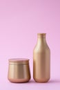 Set of cosmetic bottles with copy space, empty place for text. Golden flacon of shampoo and jar of mask on pink background. Hair Royalty Free Stock Photo