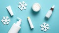 Set of cosmetic products and snowflakes on pastel blue background. Winter skin care concept. Pump bottle, lipstick, cream jar, Royalty Free Stock Photo