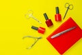 A set of cosmetic tools for manicure and pedicure. Manicure scissors, cuticles, saws, miller and red notebook stand on a yallow
