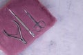 A set of cosmetic tools for manicure and pedicure stand on a pink fluffy notebook for recording clients. tweezers, scissors and