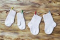 Set of cute knitted cashmere newborn baby socks and gauntlets hanged on pins against wooden background